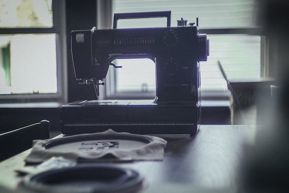 A sewing machine and embroidery hoops sit on a desk.